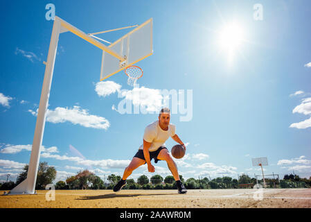 L'uomo giocare a basket sulla corte giallo, dribbling Foto Stock