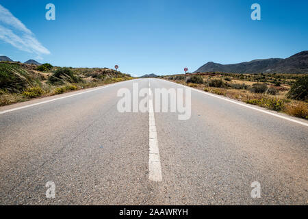 Spagna, Andalusia, Cabo de Gata, diminuendo prospettiva di autostrada vuota sulla giornata di sole Foto Stock