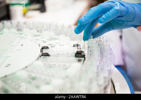 Persona di raccolto in guanti in lattice del prelievo dei campioni il lavoro in laboratorio moderno Foto Stock