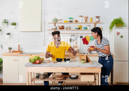 Multietnica giovane ridendo, breakfasting insieme in cucina Foto Stock