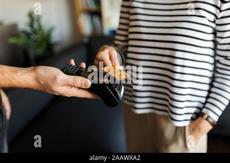 Close-up di donna pagando con carta di credito a casa Foto Stock