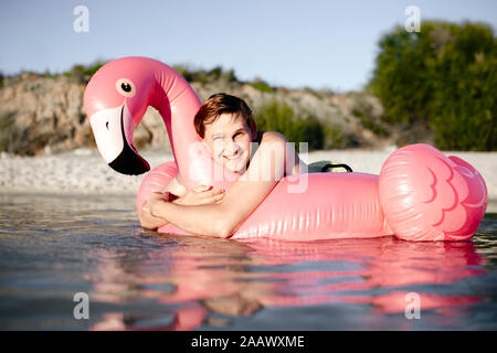 Giovane con flamingo piscina galleggiante sul lago Foto Stock