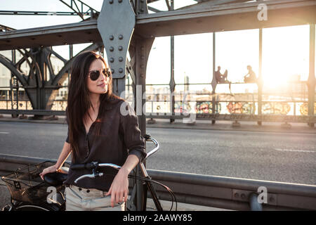 Giovane ciclista su un ponte al tramonto Foto Stock