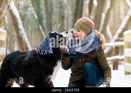 Donna che gioca con il suo cane nella neve Foto Stock