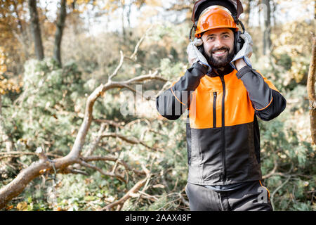 Vita-up verticale di un professionista lumberman indossando indumenti protettivi, la preparazione per la registrazione lavoro in pineta Foto Stock