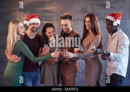 Nuovo anno sta arrivando! Il gruppo di allegro giovani persone multietnica in cappelli di Babbo Natale sul partito, che presentano uno stile di vita emotiva concetto di persone Foto Stock