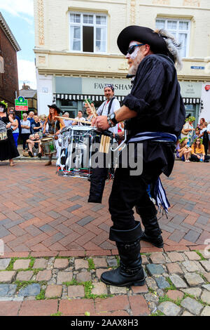 Uomo maturo dal Drumskullz drumming gruppo a Faversham Hop Festival. In street e vestito in costume di pirati e faccia bianca make up. Foto Stock