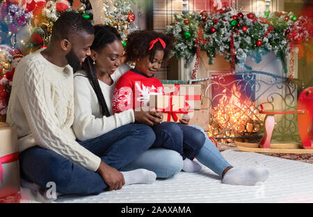 Adorabili poco ragazza afro ricevute regalo di Natale da i suoi genitori Foto Stock