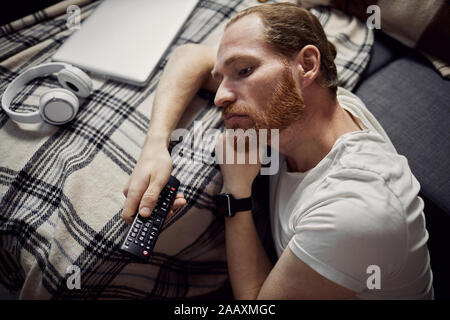 Alta Vista angolare in corrispondenza di uomo adulto che dorme sul divano mentre si guarda la TV di notte, spazio di copia Foto Stock