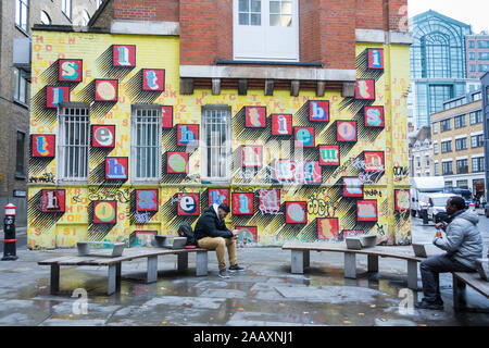 'Alphabet House' arte di strada da Ben Eine - alfabeto colorato lettere su un mattone giallo parete in Spitalfields, East London, Regno Unito Foto Stock