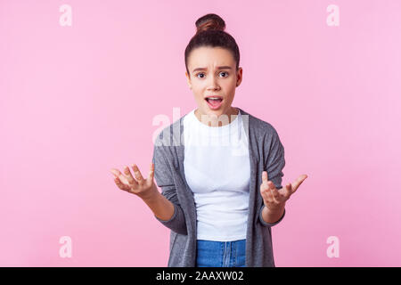 Come avete potuto. Ritratto di brunette teen ragazza con bun hairstyle in abiti casual alzando le mani chiedendo perché, cercando indignati orinato, rendendo clai Foto Stock