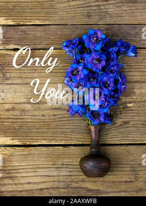 Bouquet di molto luminoso e colorato delphinium blu fiori in un piccolo vaso di creta sul legno rustico squallido sfondo usurati, piatto di laici che, vista dall'alto, clo Foto Stock