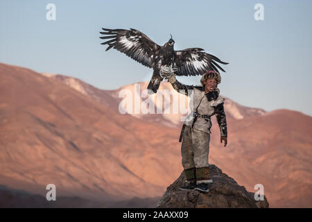 Ritratto di una giovane aquila kazaka cacciatore con la sua maestosa aquila reale nella steppa. Ulgii, Mongolia. Foto Stock