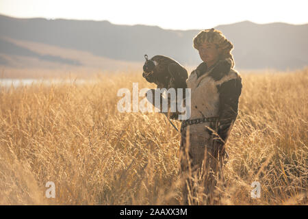 Ritratto di una giovane aquila kazaka cacciatore con la sua maestosa aquila reale nella steppa. Ulgii, Mongolia. Foto Stock