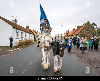 Athelstaneford, East Lothian, Scozia, Regno Unito. Il 24 novembre 2019. Si intraversa Festival: il primo giorno del festival annuale di mark St Andrew's Day avviene nel luogo di nascita della Scottish bandiera nazionale dove la si intraversa apparve nel cielo come un buon auspicio quando il Picts & scozzesi hanno sconfitto i sassoni guidati da Athelstan. Nella foto: Craig Donnelly su una fragola Stefano Clydesdale mare con lo sposo/proprietario Arthur Greenan con gli abitanti di un villaggio a sfilare lungo la strada principale Foto Stock