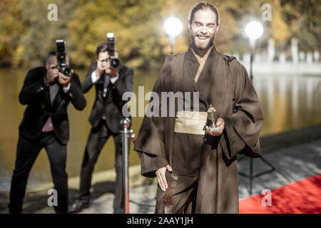 Uomo in costume come un ben noto personaggio del film a piedi con fastidiose foto Reporters sul tappeto rosso durante la cerimonia di premiazione Foto Stock