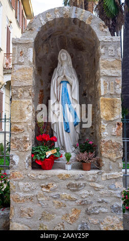 Vista ravvicinata della statua della Madonna e porta d'ingresso della Chiesa di San Pietro in piccolo villaggio in Francia Foto Stock