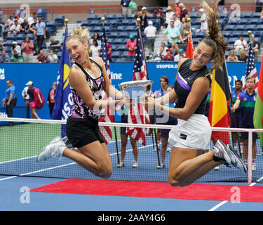 Vista laterale di Aryna Sabalenka e Elise Mertens jumping tenendo trofeo durante la presentazione del trofeo nel 2019 US Open Tennis Tournament, New York Cit Foto Stock