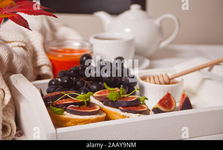 Panini con la crema di formaggio, fichi e miele sul bianco vassoio. Colazione sana nozione di cibo. Foto Stock