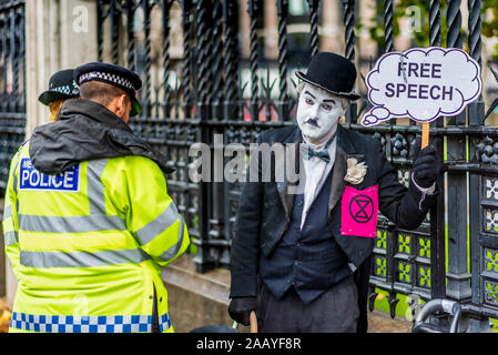 Discorso libero Parlamento britannico. Questione di polizia una ribellione di estinzione protester vestito di Chaplin tipo vestiti al di fuori della sede del parlamento di Londra. Foto Stock