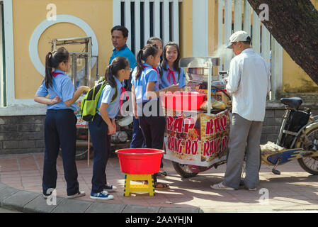 HUE, VIETNAM - Gennaio 08, 2016: Vietnamese studentesse acquistare popcorn da un venditore ambulante Foto Stock