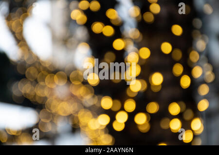 Abstract sfondo bokeh di fondo giallo luci, i rami di un albero in inverno con il blu del cielo e la neve e il paesaggio naturale, la calda sensazione di Natale Foto Stock