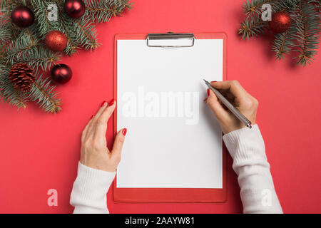 Donna scrive gli obiettivi, checklist, piani e sogni per il nuovo anno. La lista dei desideri per Natale. Elenco impegni per l'anno 2020 sul rosso. Dono di pianificazione di spesa. Top vie Foto Stock