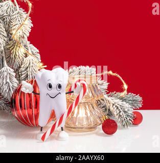 Dentista felice Buon Natale e Anno Nuovo composizione con dente sano holding candy cane. Carta regalo web banner modello con copia spazio. Foto Stock