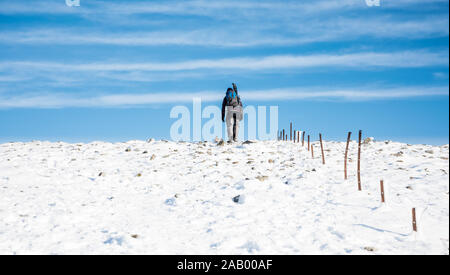 Lone walker si arrampica sulla sommità del bianco della neve ridge. Il trekking in condizioni invernali. Foto Stock