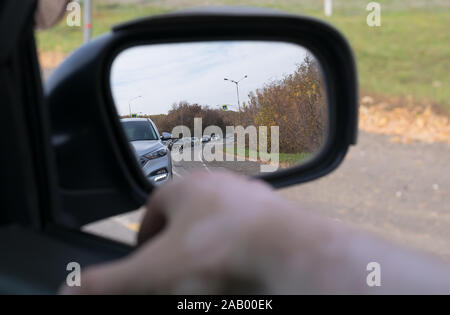 Man mano che giace sulla vettura porta con una vista dalla finestra e con una vista delle vetture in coda il retrovisore Foto Stock