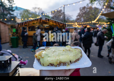 Natale tradizionale mercato invernale di alimenti in Germania Svizzera e Austria formaggio raclette su una fetta di pane Foto Stock