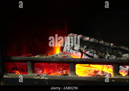 Accogliente fuoco piacevolmente in una domestica stufa a legna. Un tizzone e rosso fiamme danzanti. Foto Stock