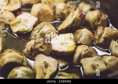 Decapare i carciofi in olio e erbe aromatiche. Italiano classico aperitivo per vino in cucina italiana. Pasto vegetariano. Foto Stock