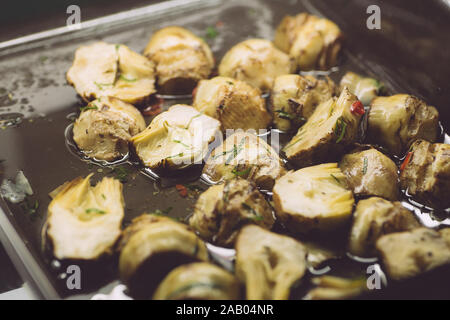 Decapare i carciofi in olio e erbe aromatiche. Italiano classico aperitivo per vino in cucina italiana. Pasto vegetariano. Foto Stock