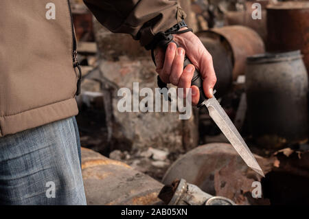 Un uomo tiene un coltello in mano. Grande coltello a baionetta in mano. Vista fron. Foto Stock