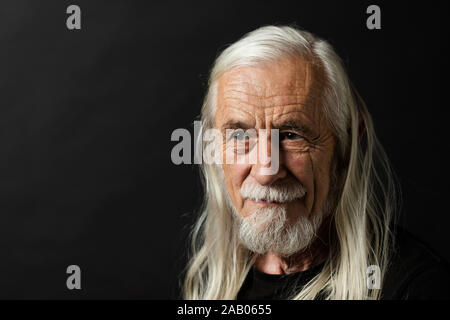 Ritratto di bella uomo vecchio con sciolto lungo i capelli grigi. L'uomo sta guardando a sinistra della foto. Foto Stock