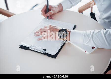 Giovane uomo segni dei documenti in ufficio vendite di successo Foto Stock