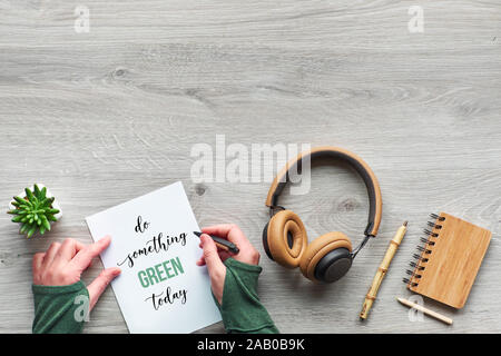 Il concetto di rifiuti zero consumo consapevole laici piana, vista dall'alto di scrittura di mani e carta. Il testo 'Do qualcosa di verde oggi", alla moda di piante succulente, bambo Foto Stock
