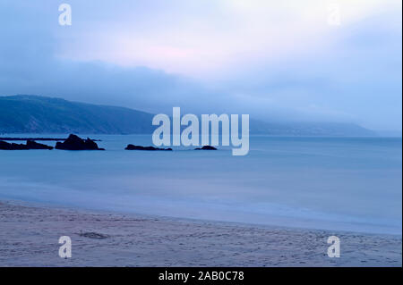 Looe Bay, Cornwall Inghilterra. Una serata opaca pesante con i cloud bassa e di un banco di nebbia drifting in oltre la linea di costa. Foto Stock