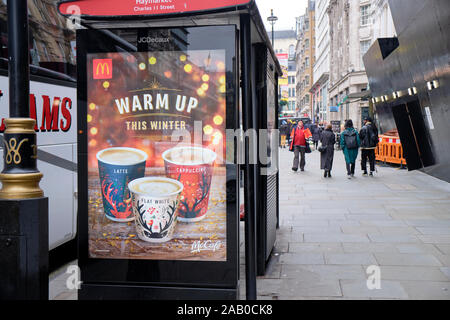 Bus McCafe shelter pubblicità che mostra le bevande calde e slogan Warm up, nel centro di Londra Foto Stock