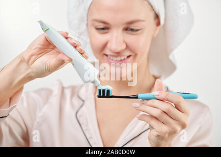 Mano di sano giovane donna applicando una pasta dentifricia su uno spazzolino da denti Foto Stock