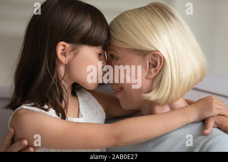 La nipote ha chiuso gli occhi naso baci di età compresa tra la nonna closeup volti Foto Stock