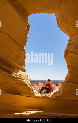 Escursionista attiva di riposo in un arco. Seduti al sole godendo la vista del deserto dello Utah. Foto Stock