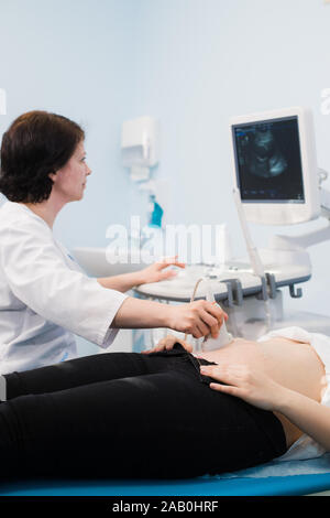 Medico di eseguire una scansione ad ultrasuoni sulla donna in stato di gravidanza Foto Stock