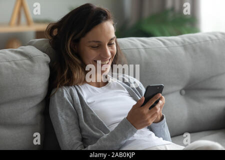 Donna appoggiata sul divano godere tranquillo weekend con lo smartphone Foto Stock