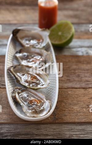 Ostriche con calce e salsa piccante. Foto Stock