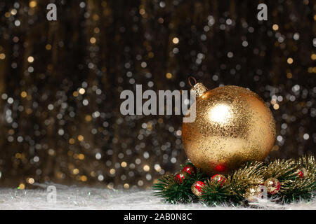 Le decorazioni di Natale composizione vista oro sfera serale con oro glitter su di esso in ghirlanda di Natale con red berrys del proprio sito su dark bac Foto Stock