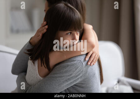 Vista ravvicinata di sconvolgere piccola figlia cuddling madre Foto Stock