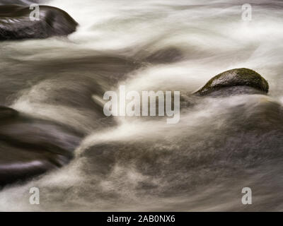 Una lunga esposizione in prossimità di un impetuoso torrente di montagna con pietre. Foto Stock