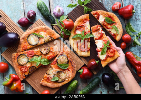 Donna mano e sano cibo vegetariano. In casa pizze italiane con verdure su oak taglieri con materie prime sopra visualizza Foto Stock